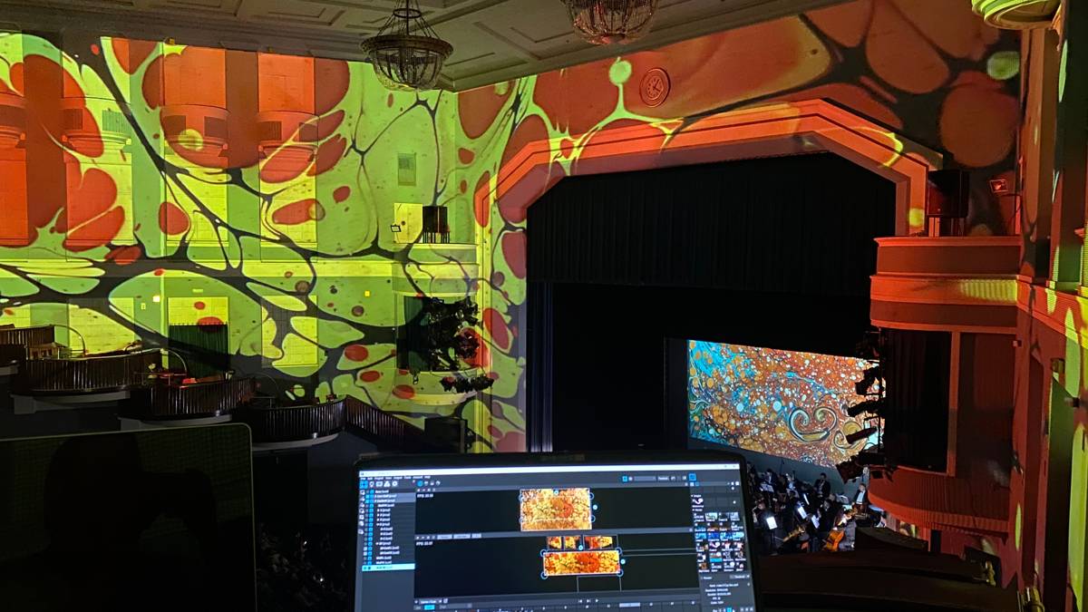 Pintura ebru proyectada sobre una gran sala de conciertos