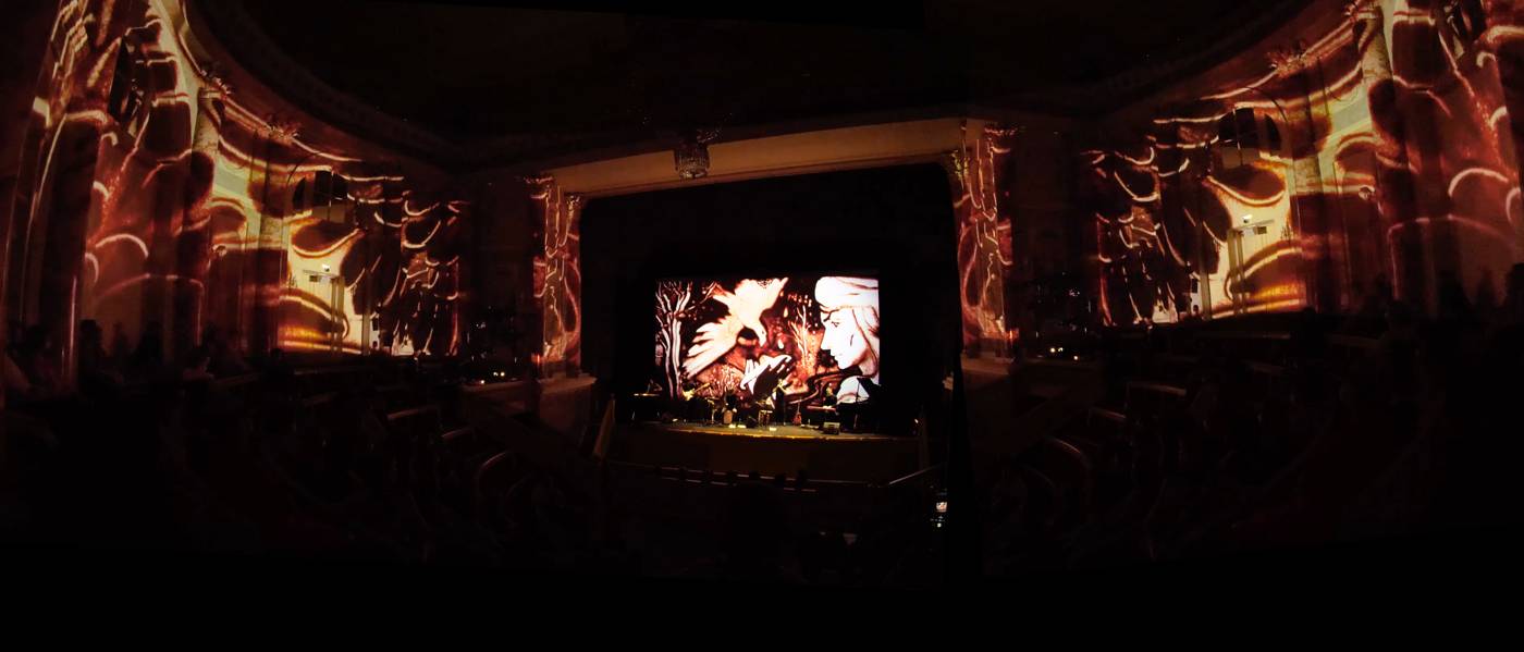 Animación en arena proyectada en el escenario y los muros de la sala