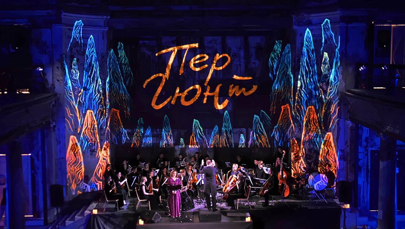 Orquesta en escena con escenografía visual proyectada sobre el fondo y los laterales